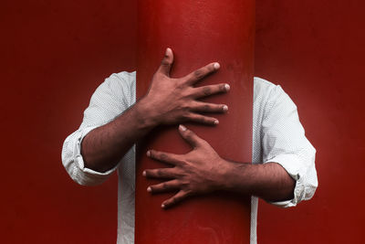 Close-up of human hand against red wall