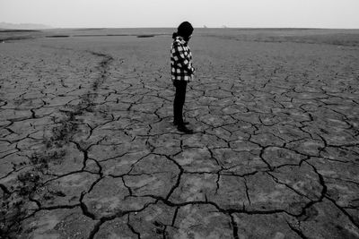 Man standing on barren, drought affected field.