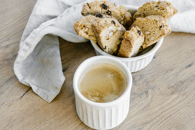 Freshly baked almond biscottis with cup of cappuccino on wooden background. 