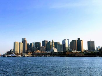 Sea by city buildings against clear sky