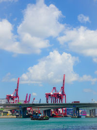 Cranes at harbor against sky