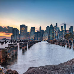 Scenic view of sea by buildings against sky during sunset