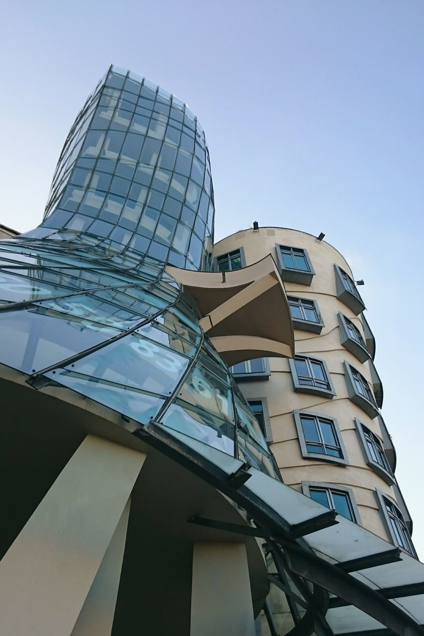 architecture, building exterior, low angle view, built structure, clear sky, modern, city, tower, tall - high, office building, building, glass - material, sky, skyscraper, day, blue, outdoors, window, architectural feature, no people