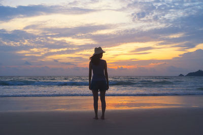 Rear view of man standing on beach during sunset