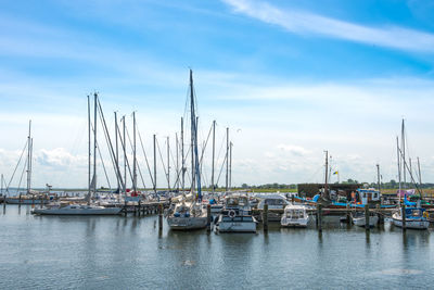 Boats moored at harbor against sky