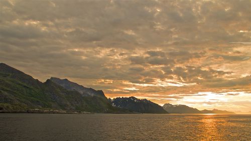Scenic view of mountains against cloudy sky at sunset