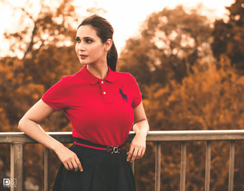 Young woman looking away while standing against railing