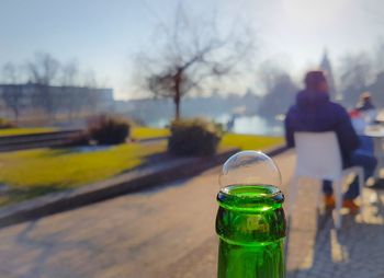 Close-up of glass bottle on street against sky