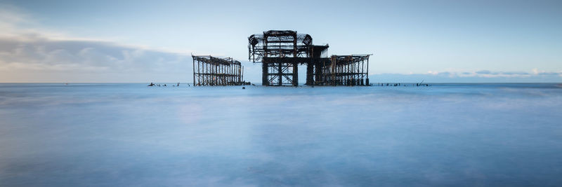 Scenic view of sea and brighton west pier against blue sky