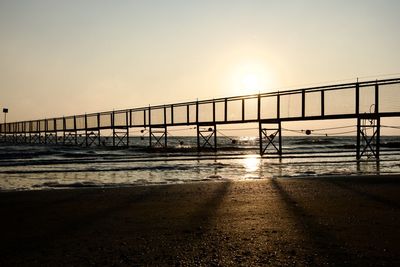 Pier over sea against sky during sunset