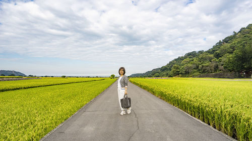 Rear view of woman walking on field against sky