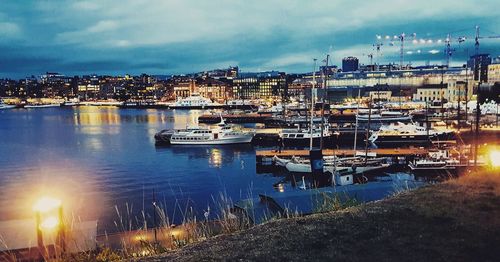 Boats in marina at harbor against sky in city