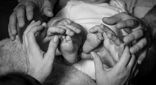 Cropped image of couple touching baby feet