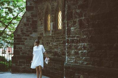 Rear view of woman standing against wall