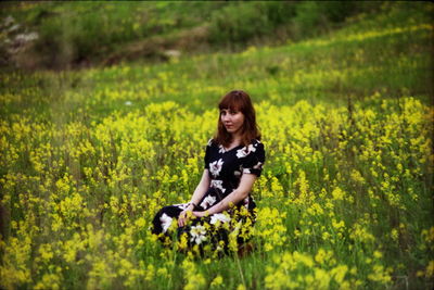 Portrait of young woman sitting on grassy field