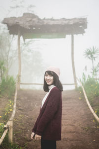 Portrait of young woman standing against trees