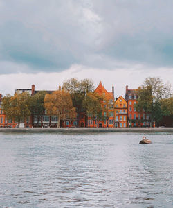 Buildings by river against sky