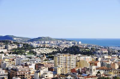 Cityscape by sea against clear sky