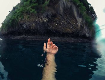 Person hand on rock in water