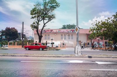 Cars on road by buildings against sky