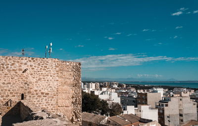 Buildings by sea against blue sky