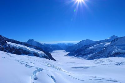 Scenic view of snow covered mountains against clear blue sky