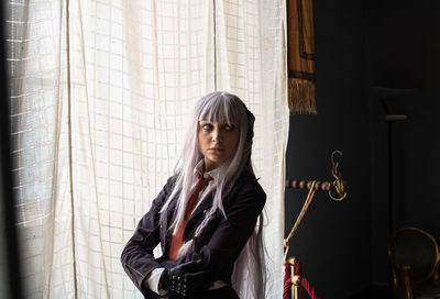 Young woman in cosplay standing against curtain