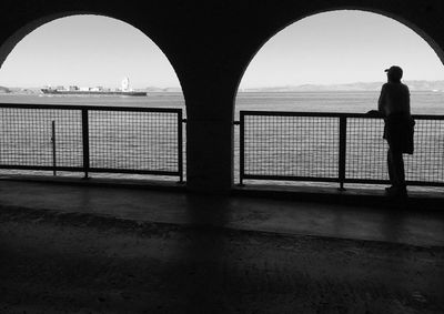 Silhouette man standing by bridge against sky