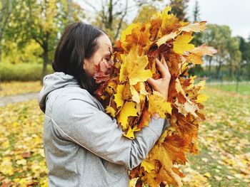 A woman smelling autumn maple leaves relaxation on nature