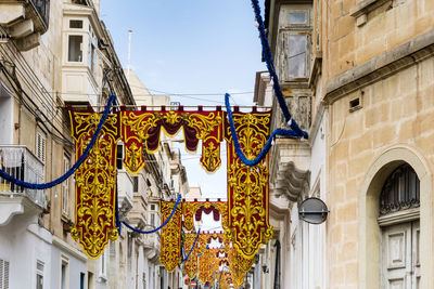 Low angle view of decorations hanging amidst buildings in city