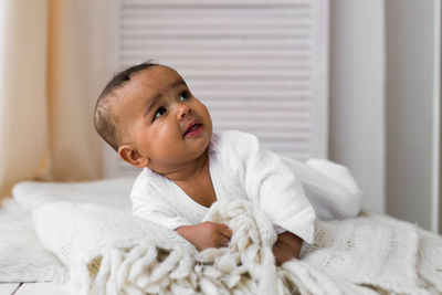 Portrait of cute baby relaxing on bed at home