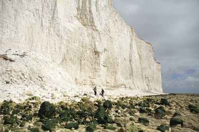 Tourists standing on rocky mountain against sky