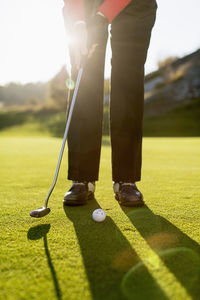 Low section of senior woman playing golf on course