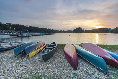 Boats moored on lake against sky during sunset