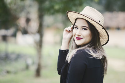 Portrait of smiling young woman standing against blurred background