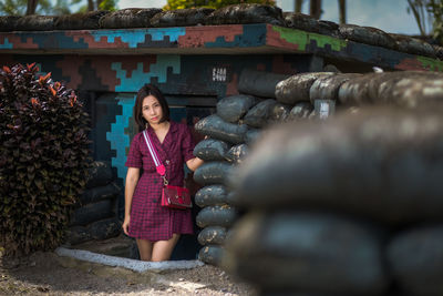 Portrait of smiling young woman standing against built structure