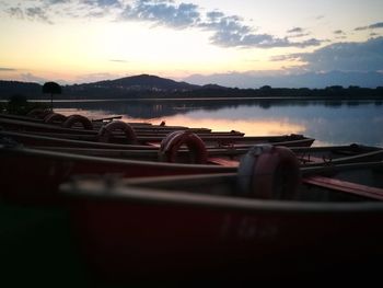 Boats moored in lake against sky during sunset