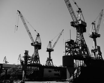 Low angle view of cranes at construction site against sky