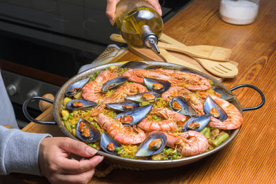 Pouring olive oil into a seafood paella, enhancing the flavors of this classic spanish 