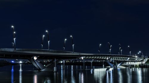 Illuminated bridge over river at night