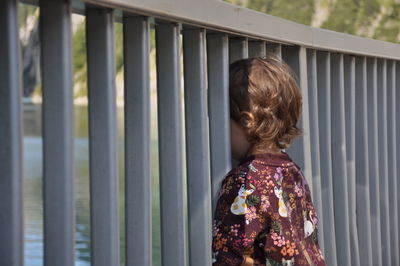 Rear view of girl standing against railing