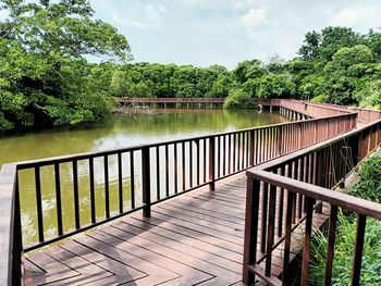 Footbridge over lake against sky