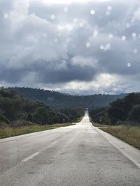 Empty road amidst trees against sky