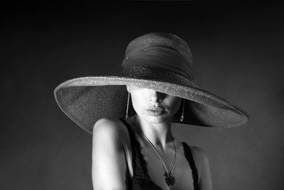 High fashion portrait of an elegant young woman in a black hat and lingerie.