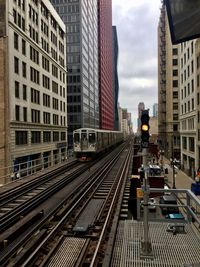 Railroad tracks amidst buildings in city against sky