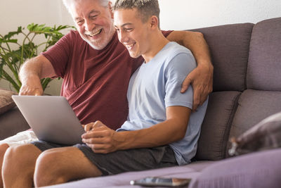 Smiling senior man and grandson using laptop at home