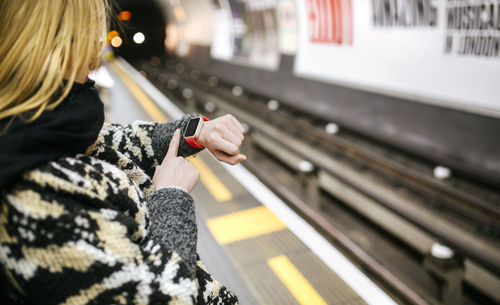 Young woman looking on her smartwatch waiting for the subway