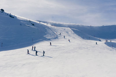 People skiing on snowcapped mountain against sky