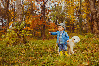 Full length of boy with dog against trees during autumn