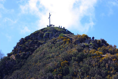 Low angle view of cross on rock against sky